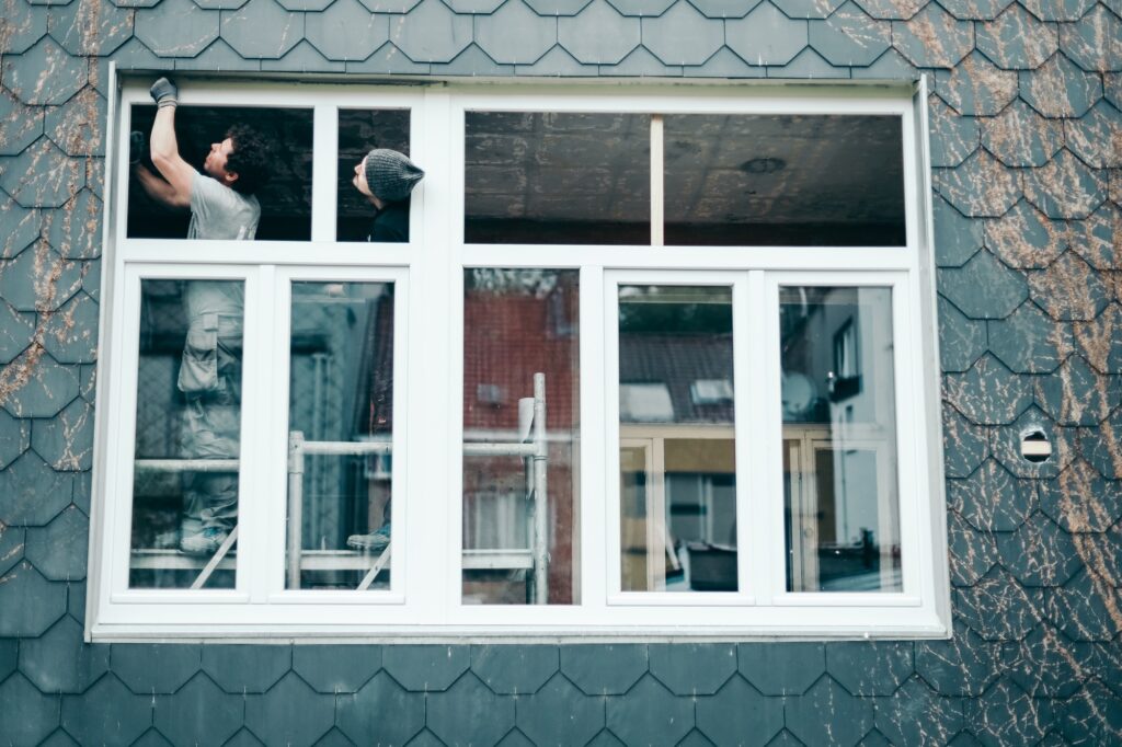 Two men are repairing a plastic window.
